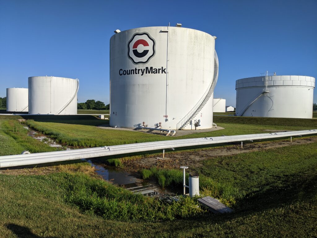 Storage tanks with CountryMark branding, surrounded by green grass and pipelines, illustrating industrial tank coatings and maintenance practices.