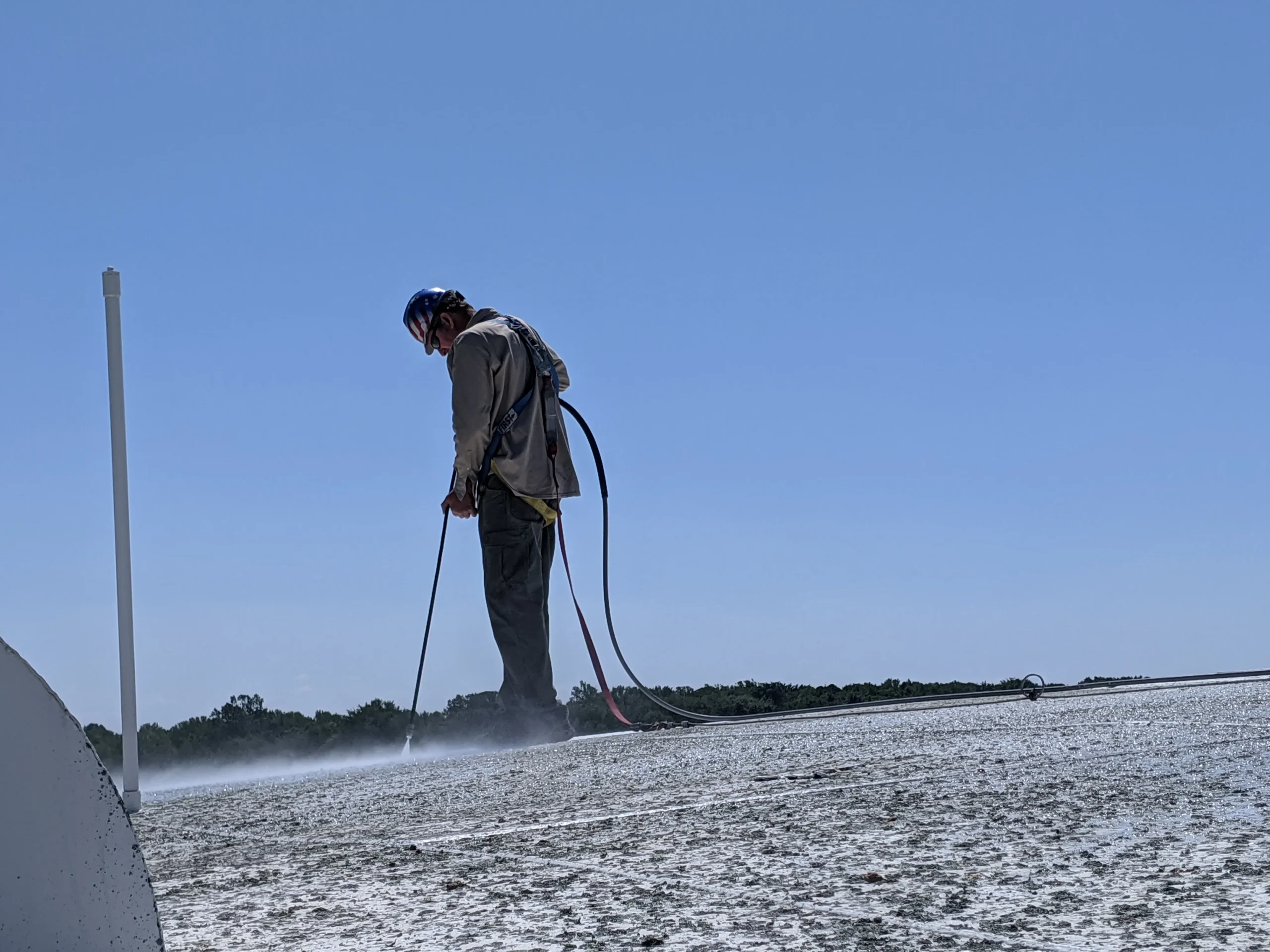 Worker using high-pressure water blasting equipment on a surface, demonstrating industrial hydroblasting technique for precision cleaning in an outdoor setting.