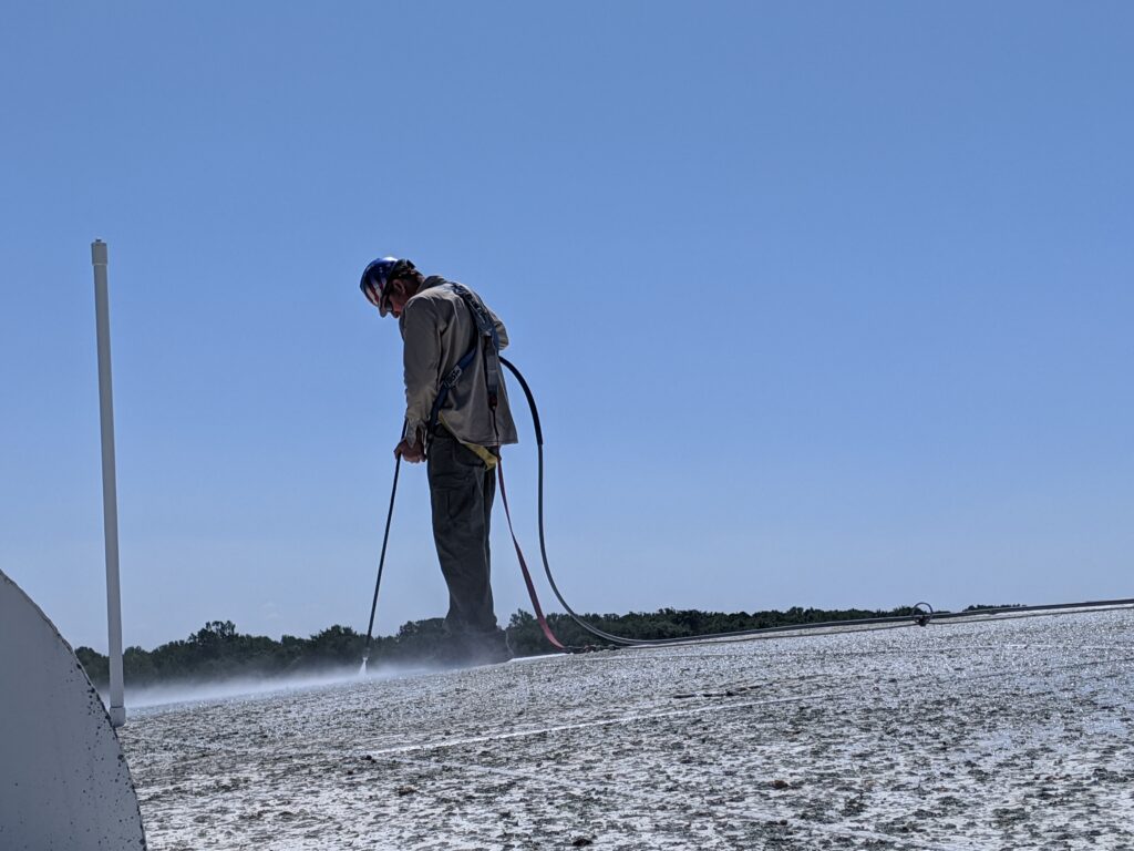 Worker using high-pressure water jet for industrial water blasting on a surface, demonstrating hydroblasting techniques in an outdoor setting.