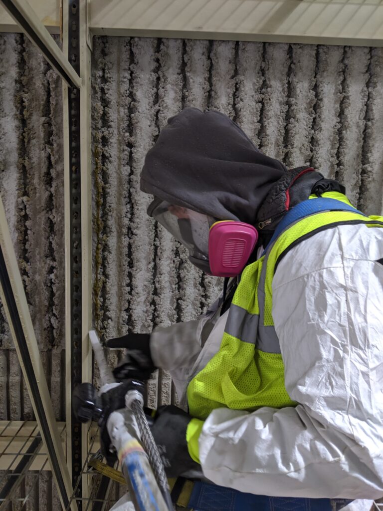 Worker in safety gear using dry ice blasting technique for industrial cleaning in Knoxville, TN, with focus on equipment maintenance and efficiency.